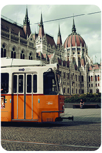 A yellow city train driving through a cobblestoned Budapest, Hungary city center